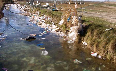 les déchets urbains s'envolent de la déchargent et atterrissent dans le cours d'eau